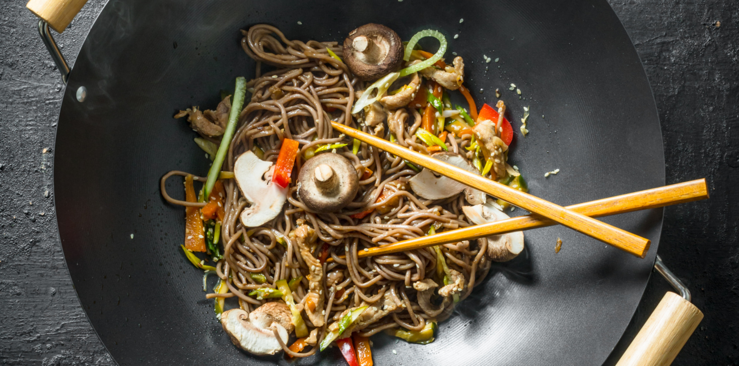 Chinese noodles wok soba in a frying pan with chopsticks.