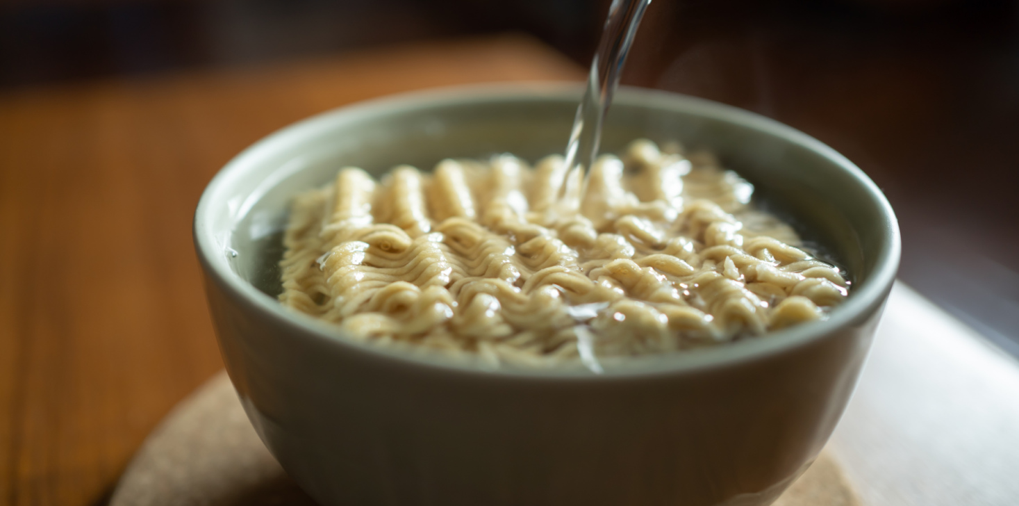 Pouring hot water into instant noodles in a bowl
