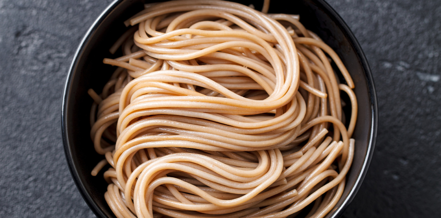 Soba noodles on a black bowl. Japanese food. Slate background. Top view.