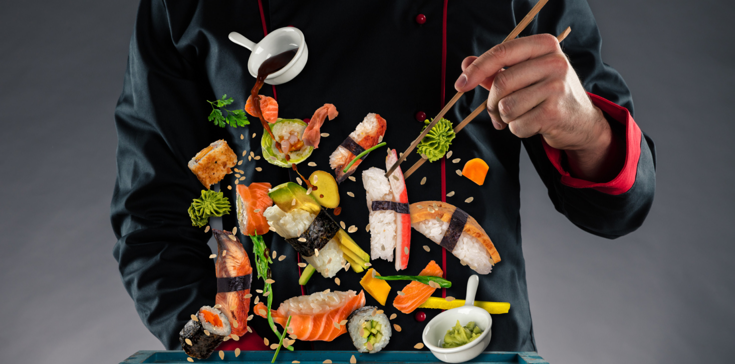 Master chef holding chopsticks with flying sushi